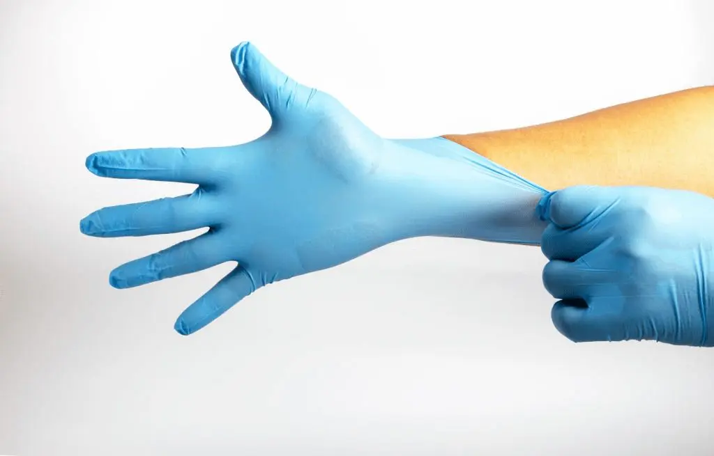 person putting on blue latex gloves
